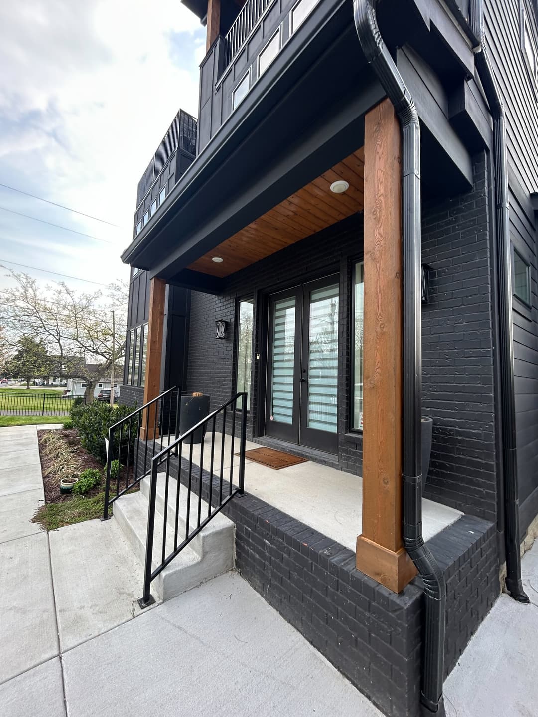 Stained cedar porch posts on a dark brick infill home on 48th Ave N, Nashville